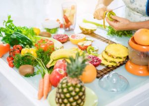 Happy senior couple preparing healthy vegetarian breakfast with fruits and vegetables